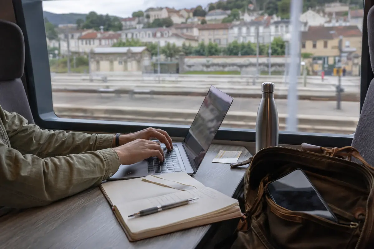 Une personne travaille dans un train français tandis que le téléphone reste rangé dans le sac.