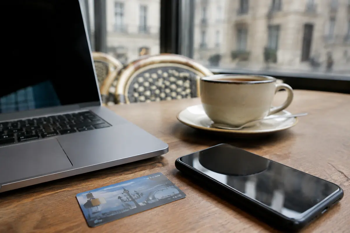 Ordinateur et téléphone utilisés côte à côte dans un café parisien