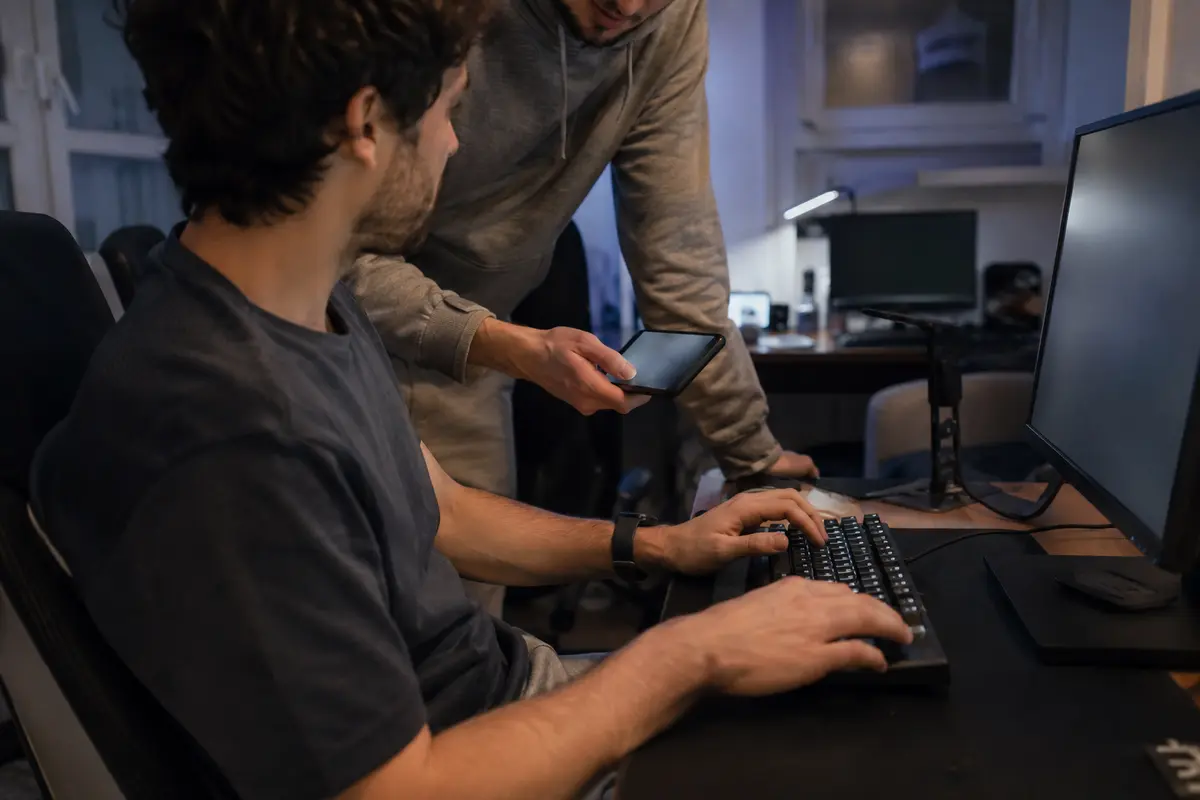 Un joueur saisit sur son ordinateur un code de vérification montré sur le téléphone de l’autre joueur