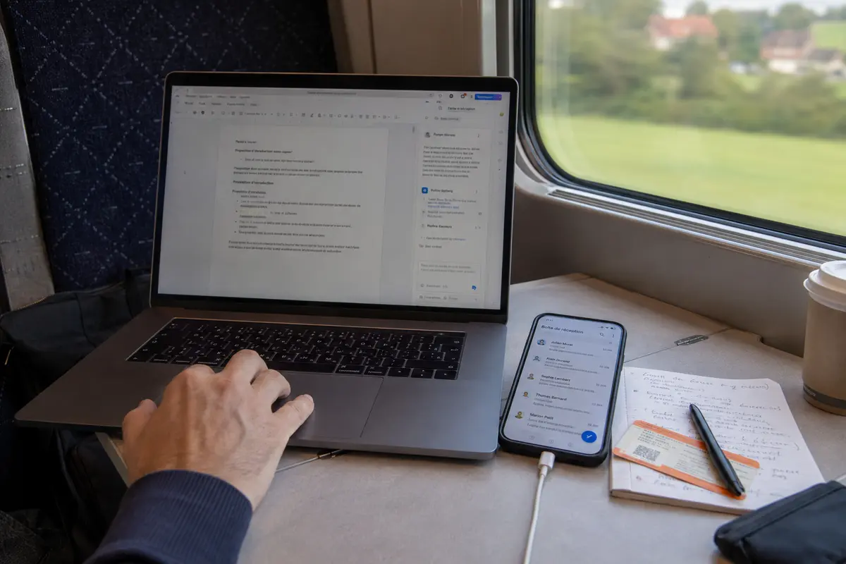 Travail sur un ordinateur et un téléphone pendant un trajet en train après avoir testé la nouvelle connexion