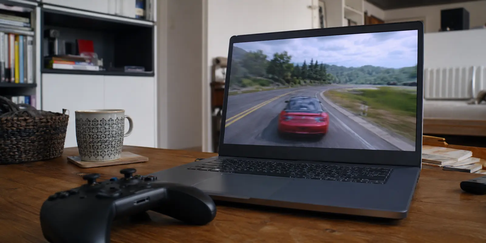 Un ordinateur portable affiche un jeu de course en streaming devenu légèrement flou, avec une manette posée au premier plan dans un appartement en France