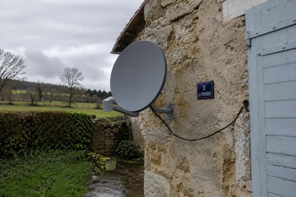 Une antenne d’accès Internet par satellite est installée sur le mur d’une maison rurale française