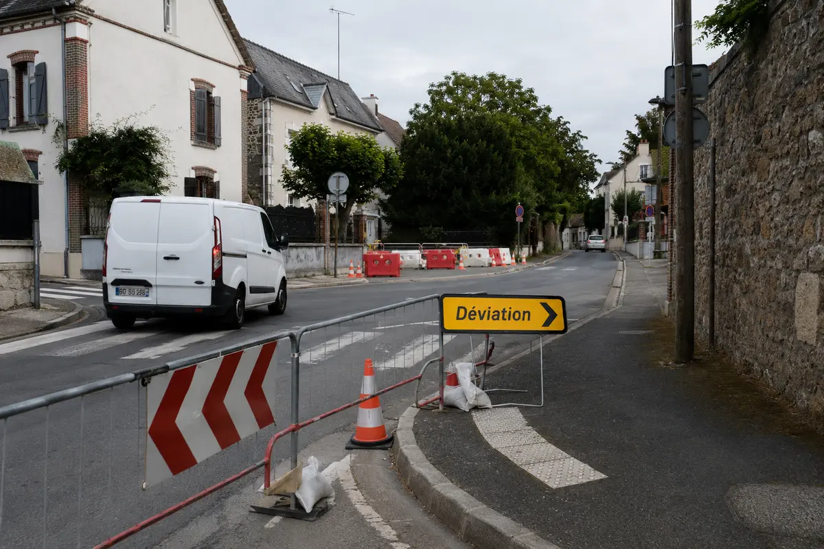 Une camionnette suit une déviation autour d’une rue barrée dans une ville française