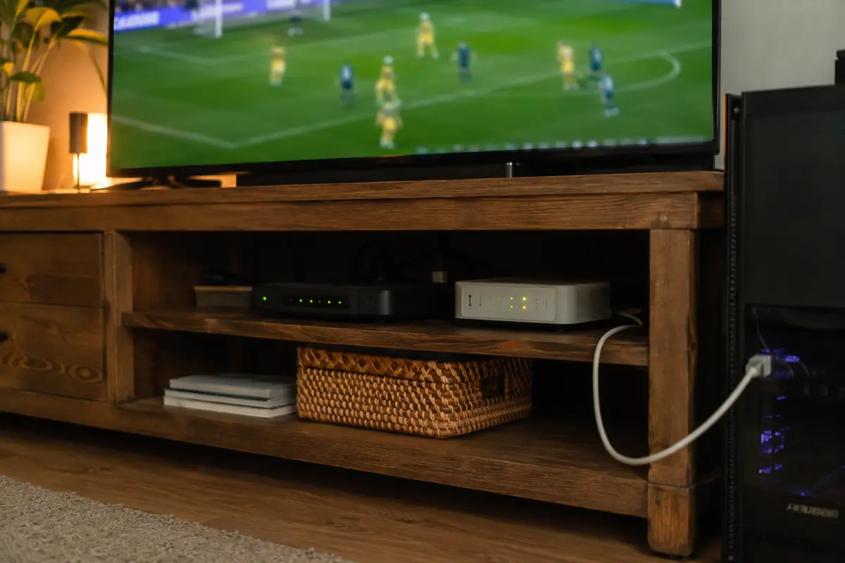 Modem e roteador sob a televisão com cabo Ethernet ligado ao computador de jogos