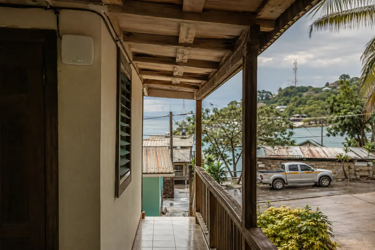 Punto de acceso Wi-Fi en el corredor de un alojamiento de Roatán con una antena celular en la colina