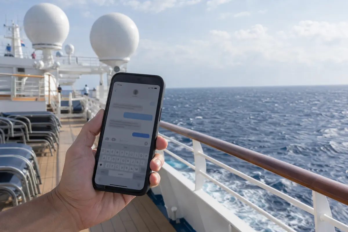 A phone using cellular data on a cruise deck at sea near the ship's communications domes.