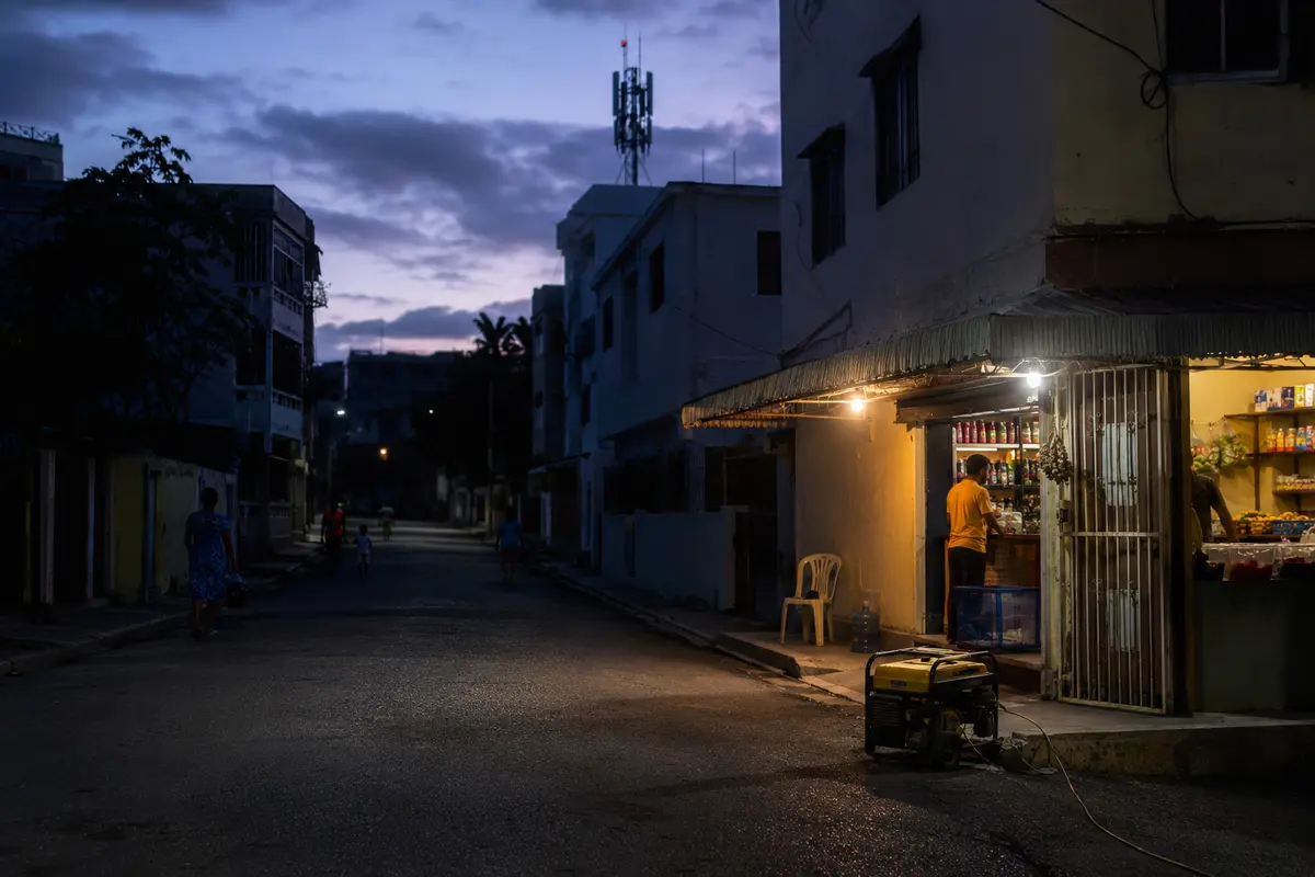 Colmado iluminado por un generador durante un apagón en un barrio de Santo Domingo con una antena celular al fondo