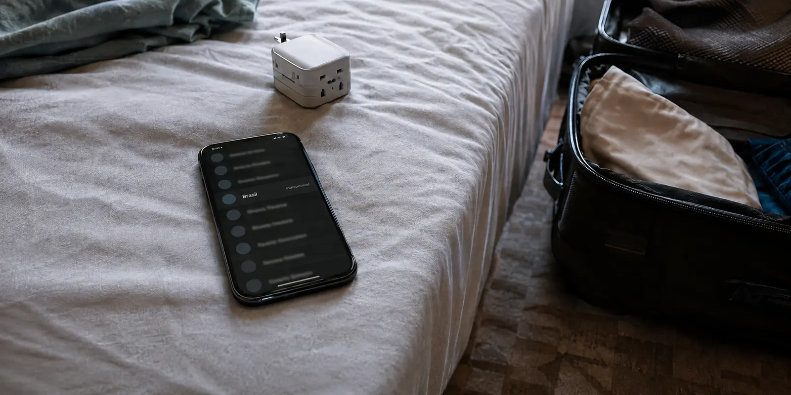 Celular em um quarto de viagem mostrando que a localização Brasil está indisponível no plano grátis