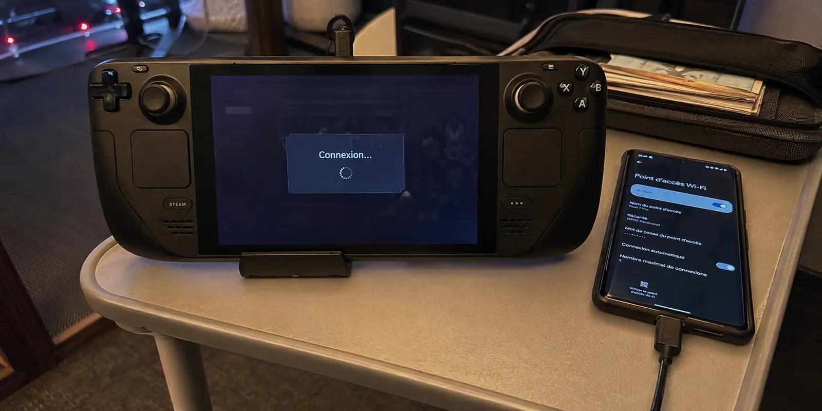 Un Steam Deck bloqué sur la connexion à un jeu en ligne à côté du téléphone utilisé en partage de connexion