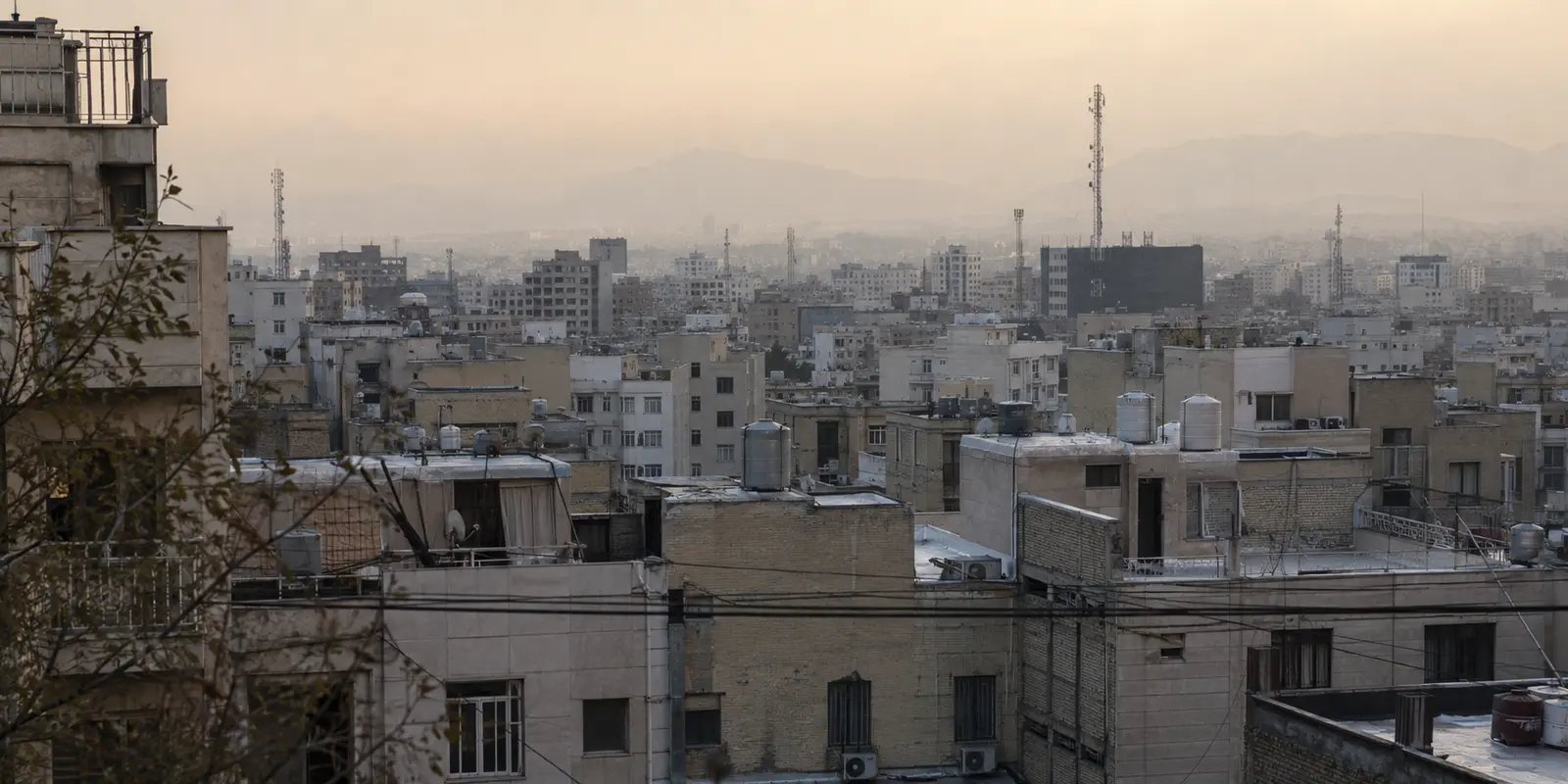 أسطح أحياء طهران وهوائياتها تحت ضباب خفيف عند المساء