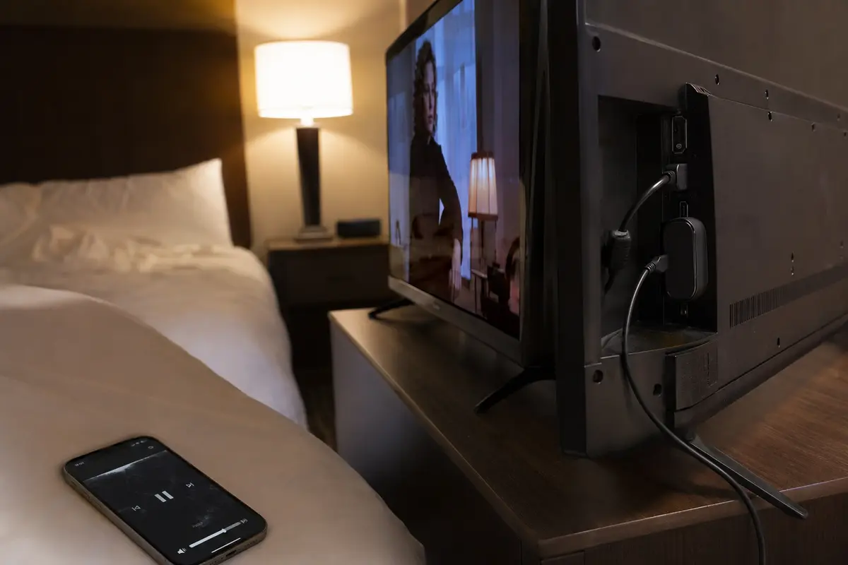 Reproductor conectado detrás del televisor y teléfono usado como mando en la habitación
