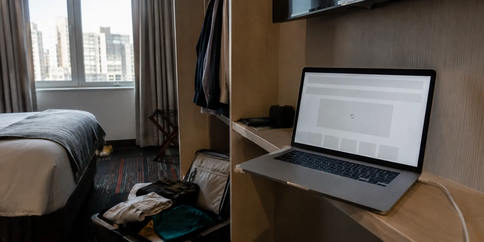 MacBook aberto em um quarto de hotel com uma página brasileira que não conclui o carregamento