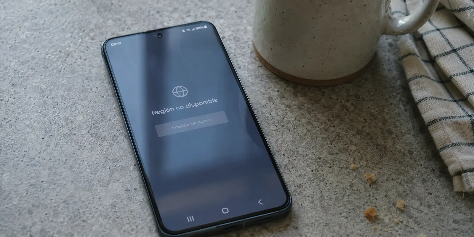 Teléfono Android que muestra un aviso de región no disponible sobre una encimera de cocina