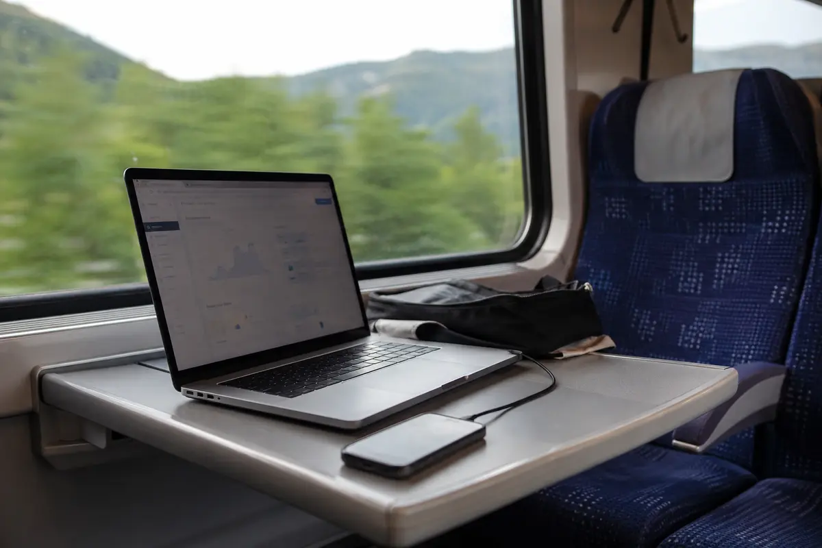 Um notebook mantém o painel de trabalho aberto em uma mesa de trem enquanto usa a conexão do telefone.