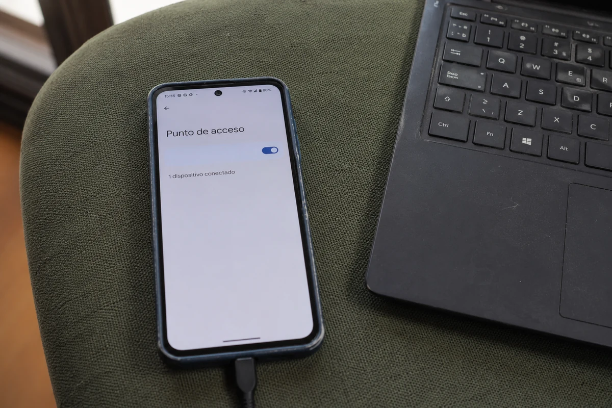 Un teléfono comparte su conexión mediante un punto de acceso junto a un portátil.