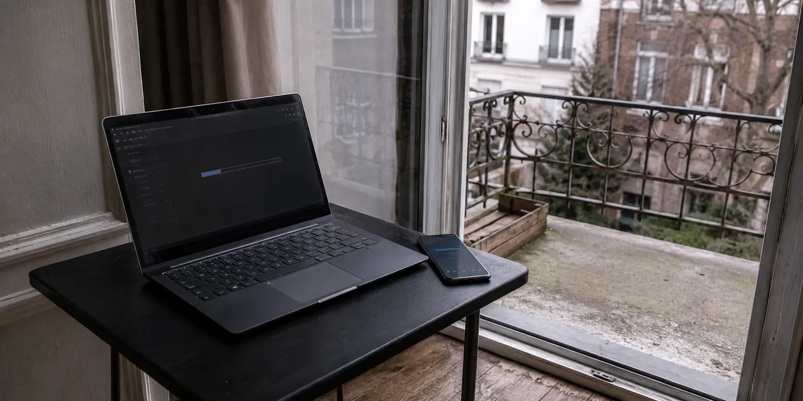 Laptop und Android-Handy an einer offenen Balkontür während eines realistischen VPN-Netzwechseltests