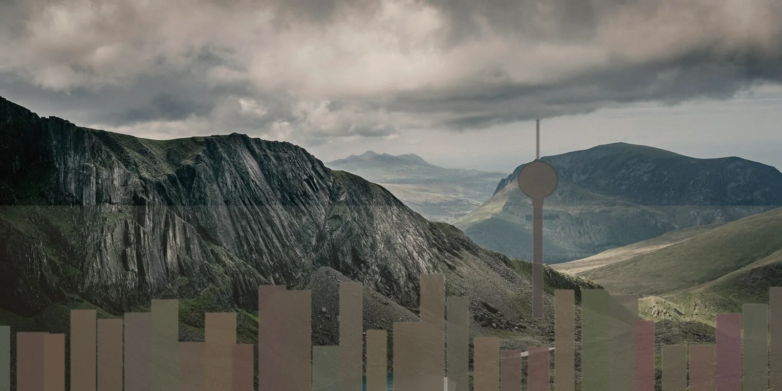 A dense city skyline beneath a mountain range in hazy late-afternoon light