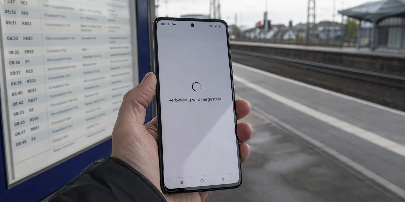 Ein Smartphone bleibt auf einem deutschen Bahnsteig trotz 5G bei der Verbindungsherstellung hängen