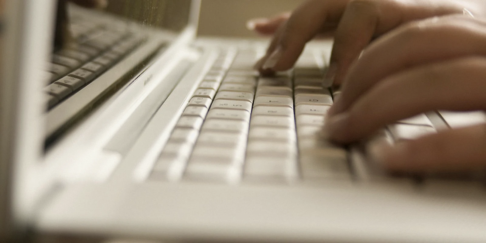 Hands typing on a laptop keyboard during remote work.