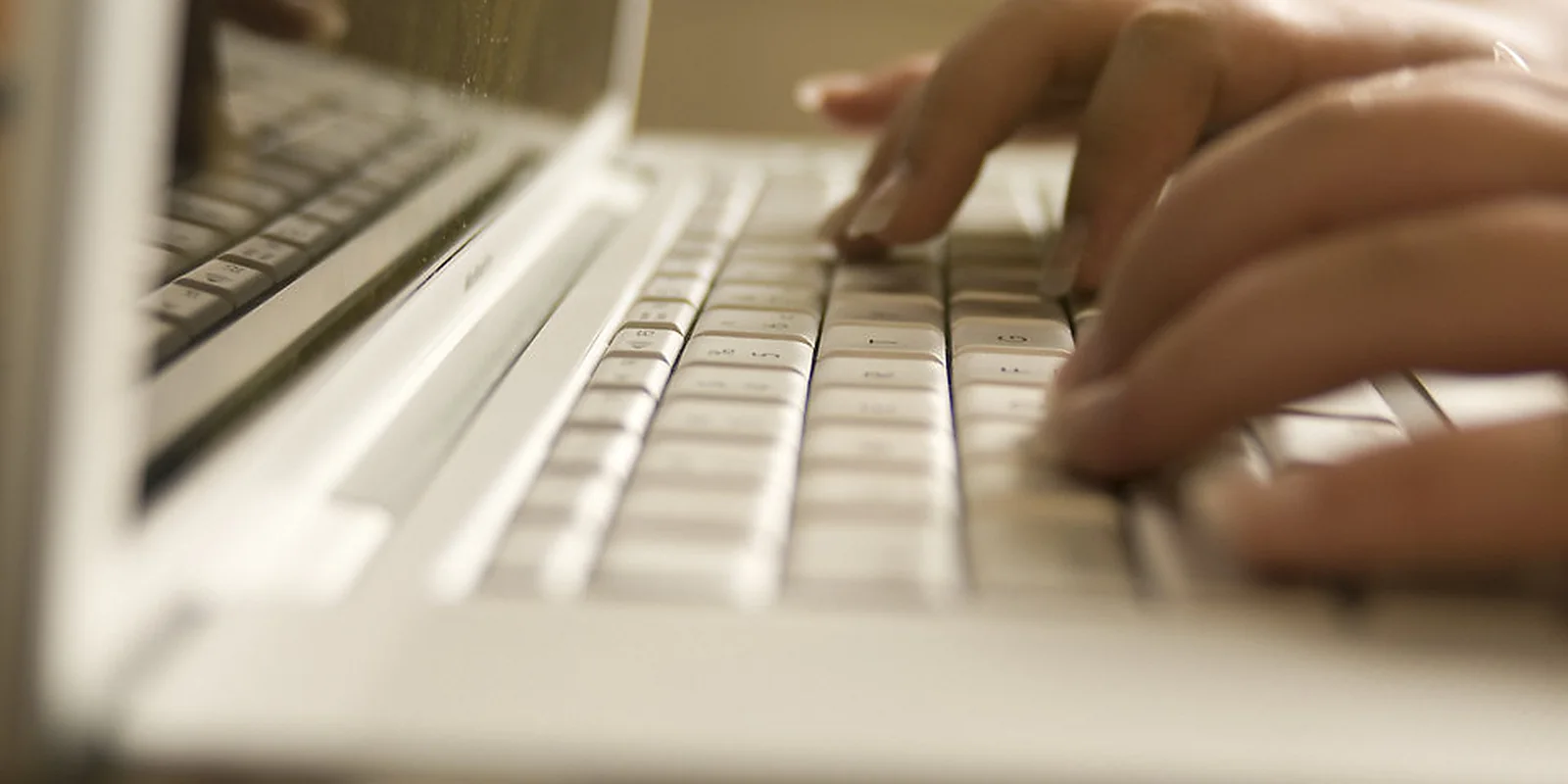 Hands entering details on a laptop during a secure online task.