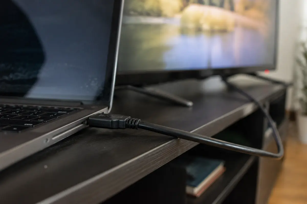 كابل HDMI يصل حاسوبًا محمولًا بتلفاز في غرفة معيشة