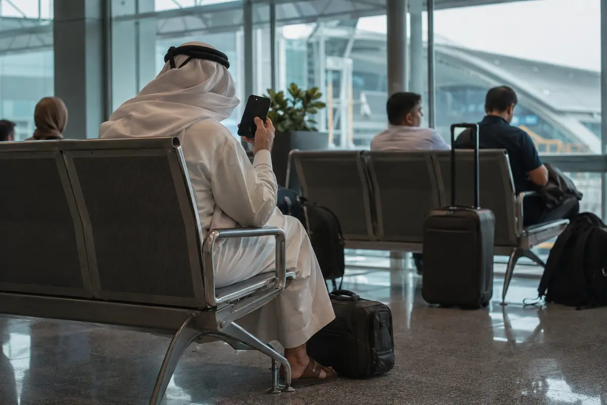 مسافر خليجي ينتظر في صالة مطار وهو يتفقد هاتفه