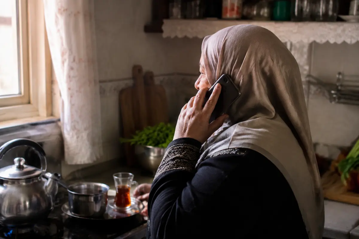 سيدة تتحدث عبر هاتفها في مطبخ منزلي هادئ