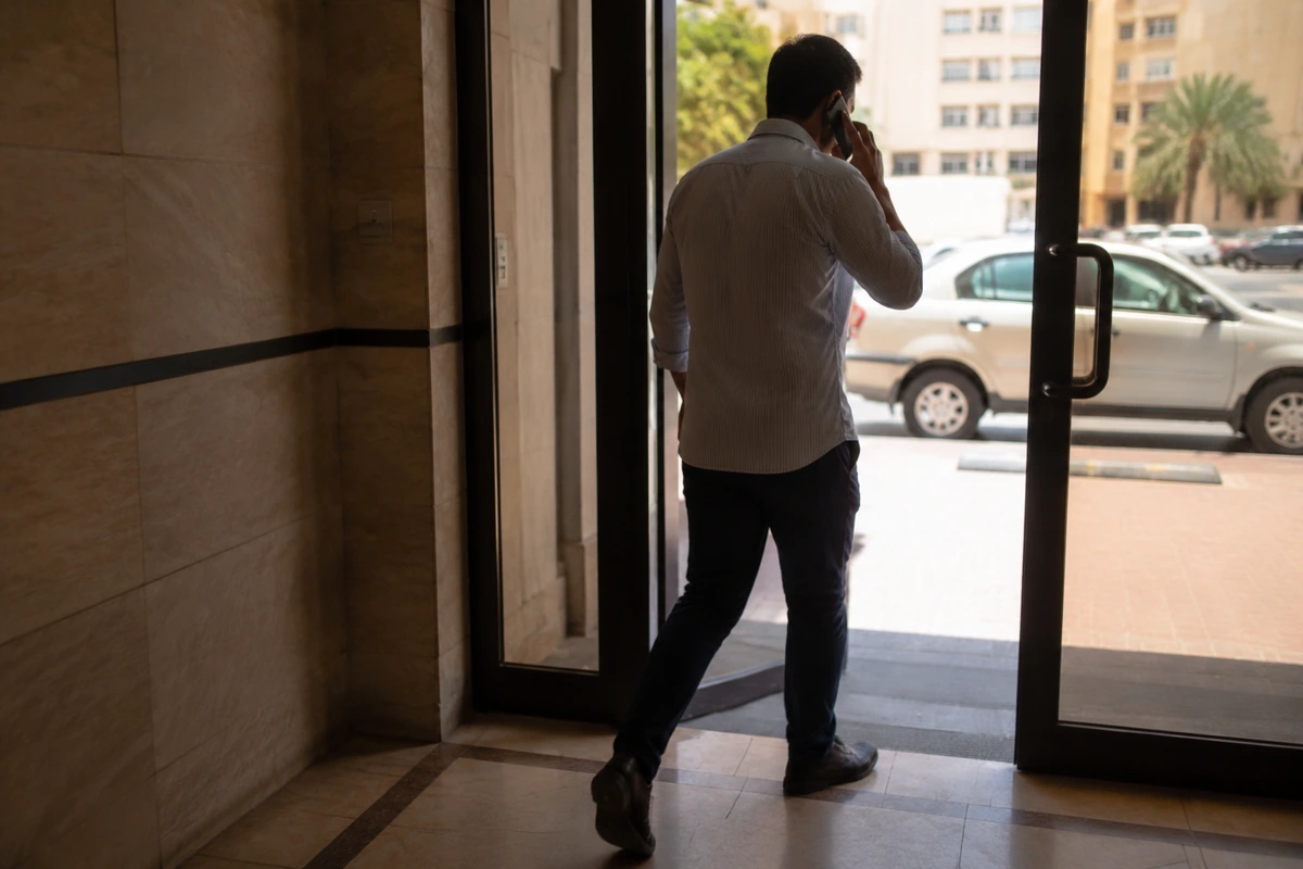 شخص يواصل مكالمة هاتفية وهو يعبر من المبنى إلى الشارع