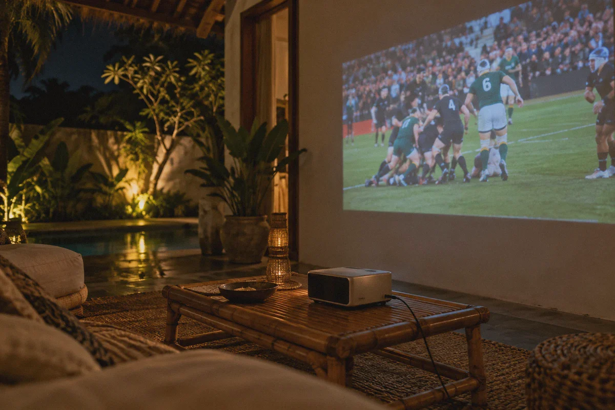Rugby broadcast projected on a villa wall at night.
