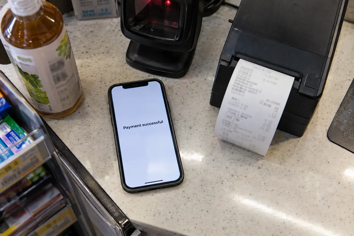 Phone shows a successful payment beside the same type of store scanner and a printed receipt