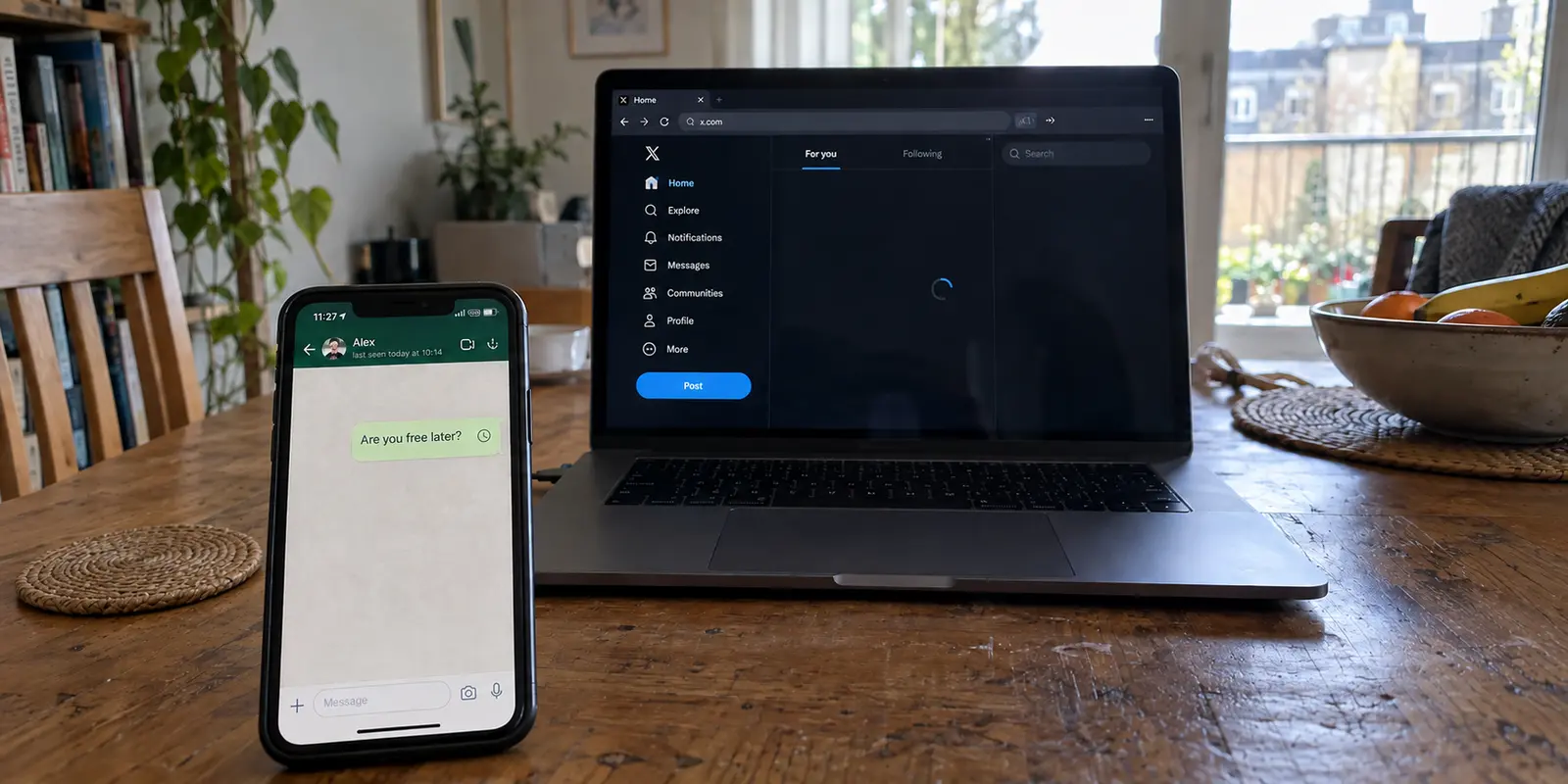 WhatsApp message pending while X remains stuck loading on a nearby laptop