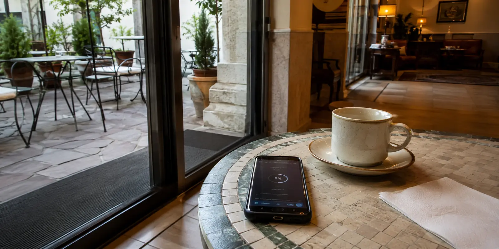 Téléphone affichant un envoi bloqué sur une table de petit-déjeuner près de l’entrée d’une terrasse d’hôtel