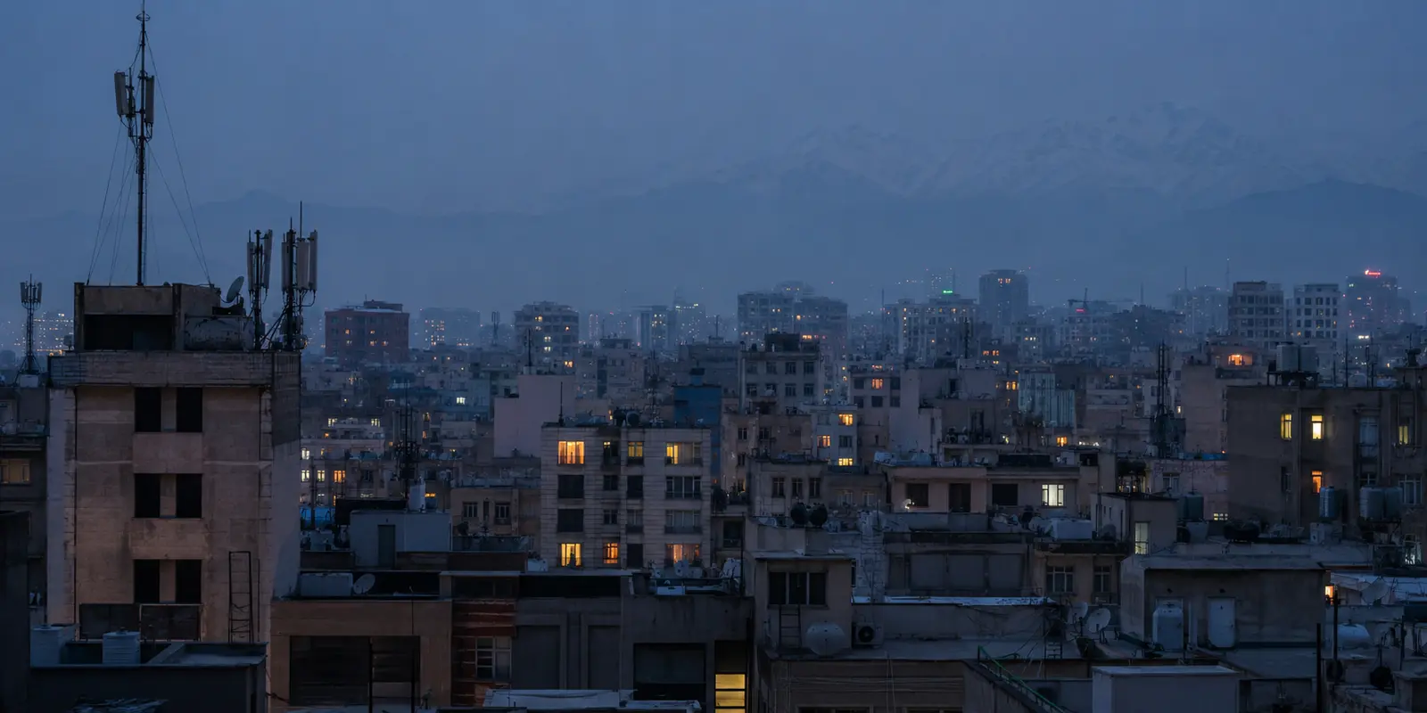أسطح طهران وهوائيات الاتصال عند الغسق والجبال خلف ضباب المدينة
