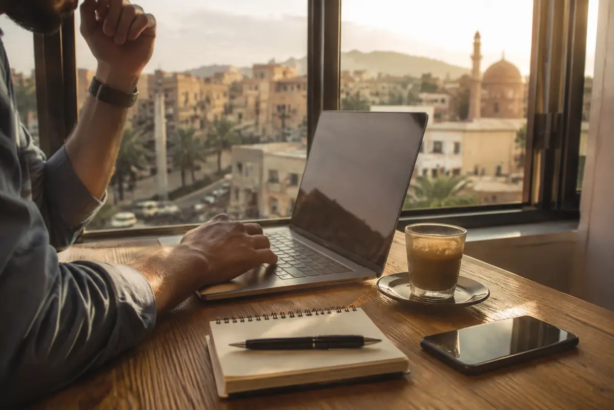 مسافر يعمل على حاسوب محمول أمام مدينة غريبة