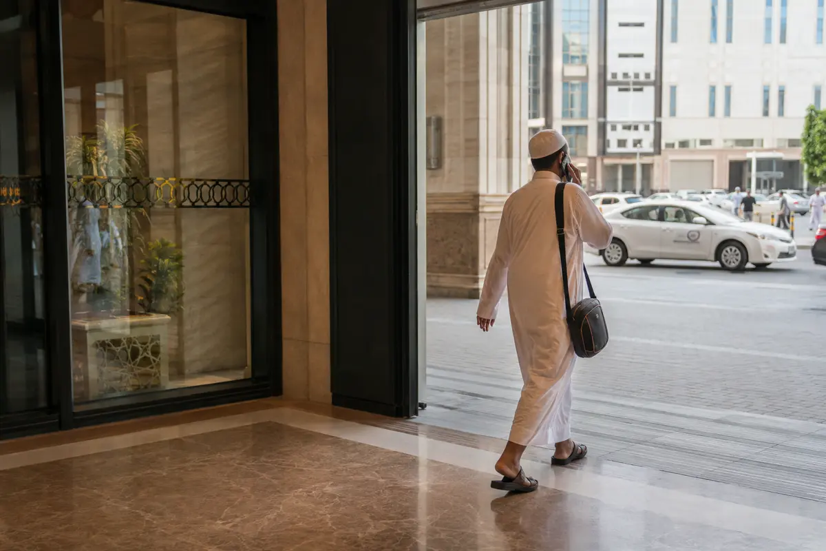 مسافر يواصل مكالمته أثناء خروجه من الفندق إلى الشارع