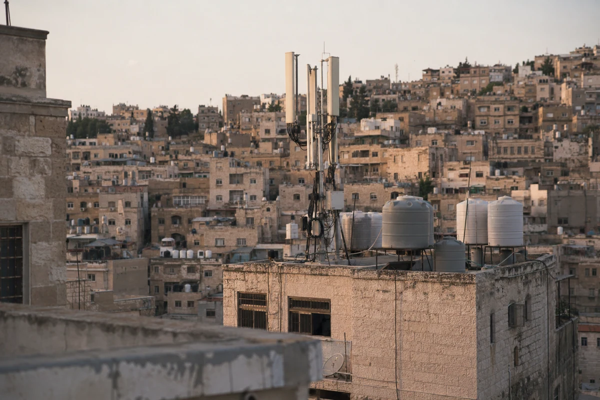 هوائيات اتصالات وخزانات مياه فوق أسطح مبانٍ حجرية في عمّان