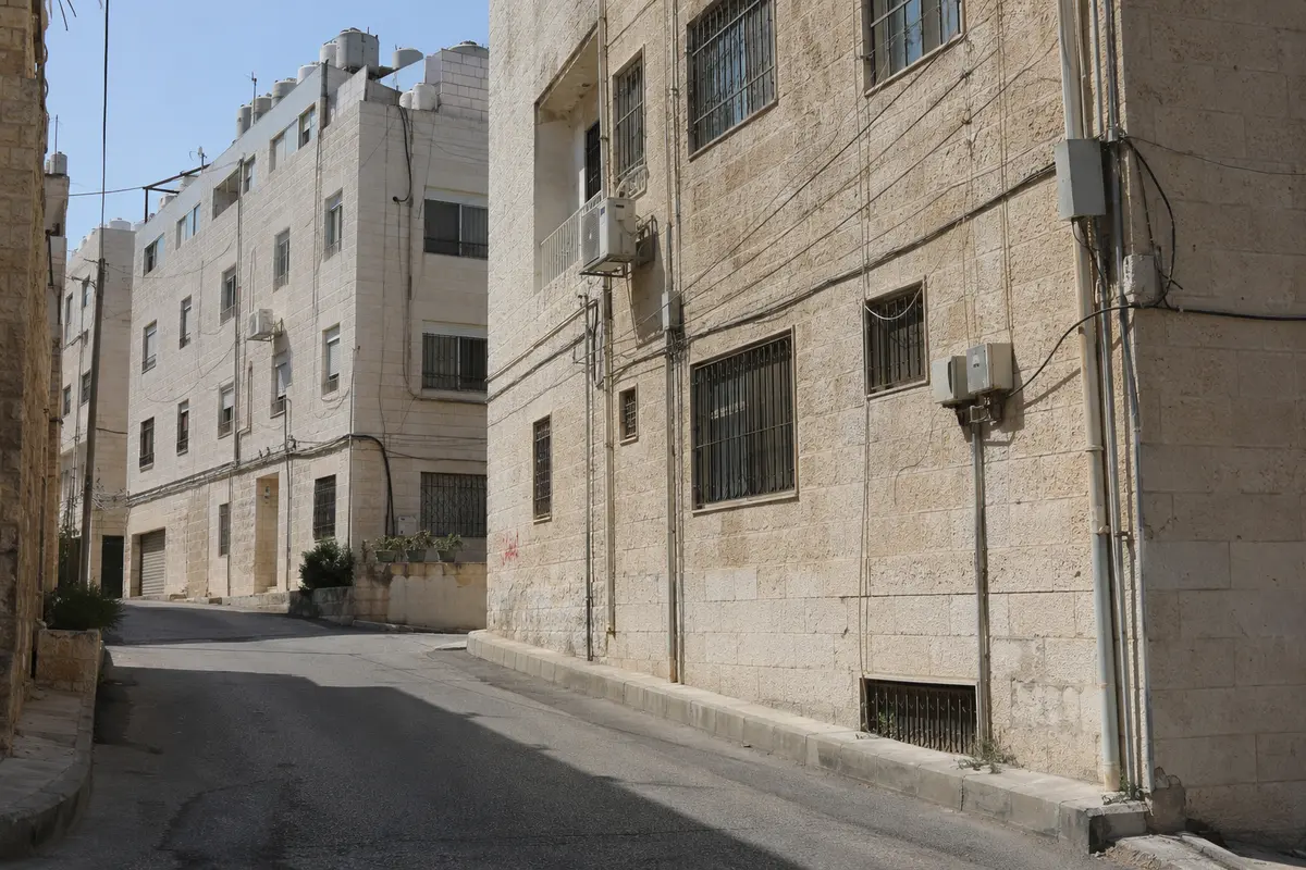 كابلات وصناديق اتصال ممتدة على واجهات مبان حجرية في عمّان