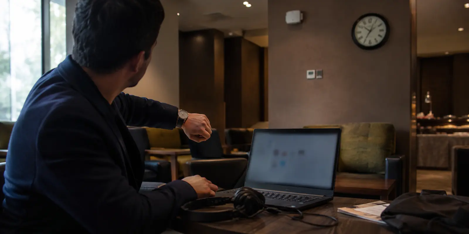 مسافر يراقب الوقت قبل اجتماع عبر شبكة فندق لا يتصل عليها VPN